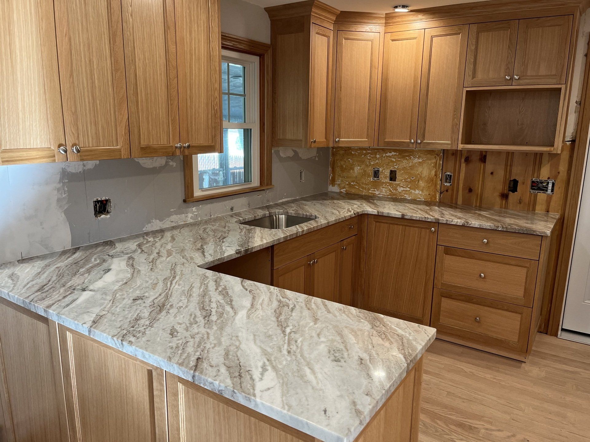 A kitchen with wooden cabinets and marble countertops