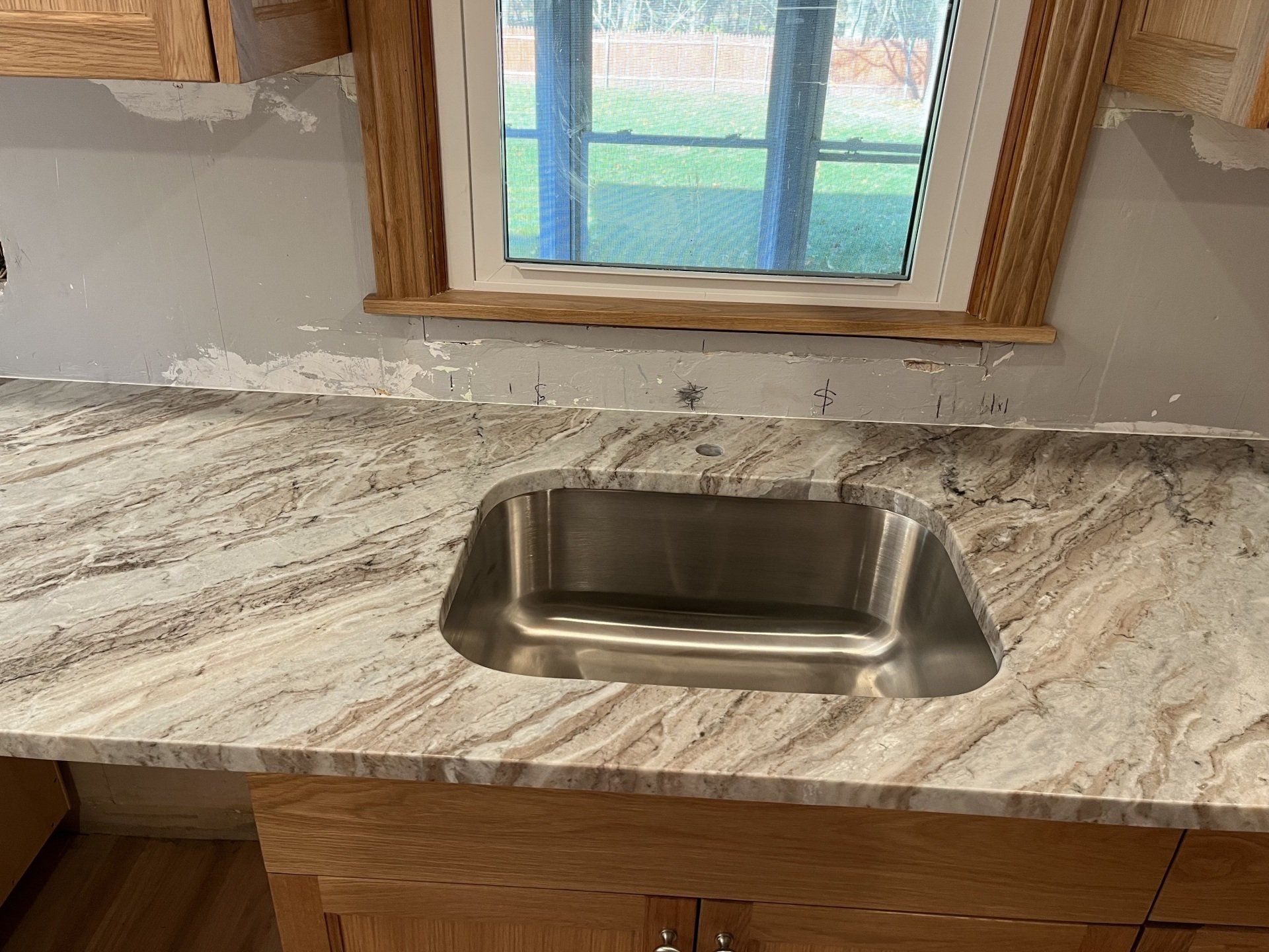 A stainless steel sink is sitting on top of a marble counter in a kitchen