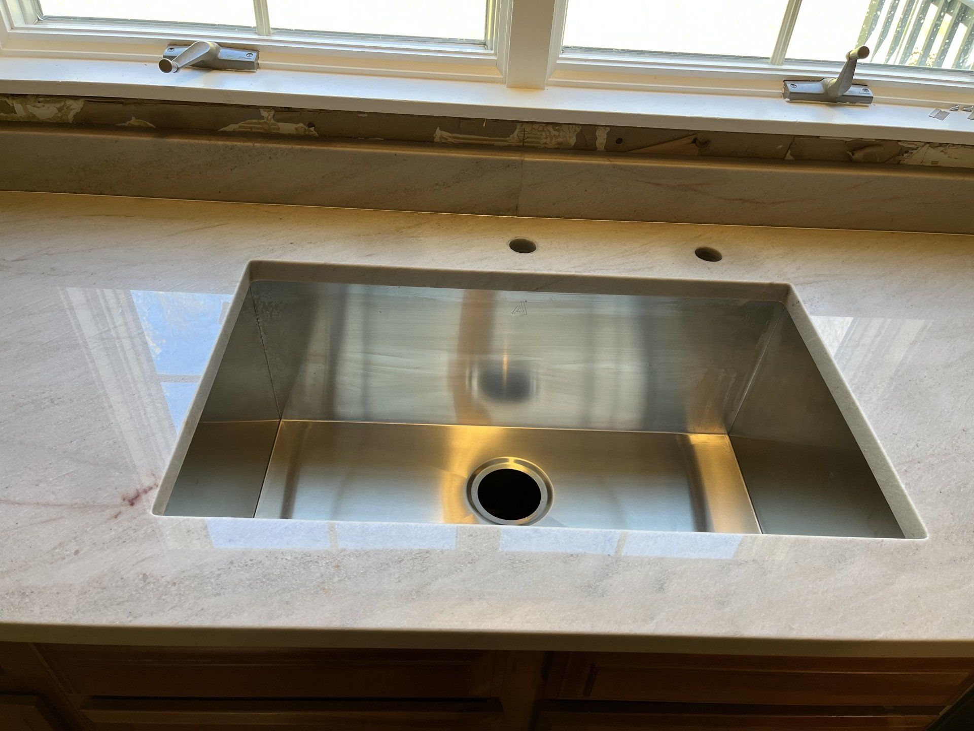 A stainless steel sink on top of a quartzite countertop