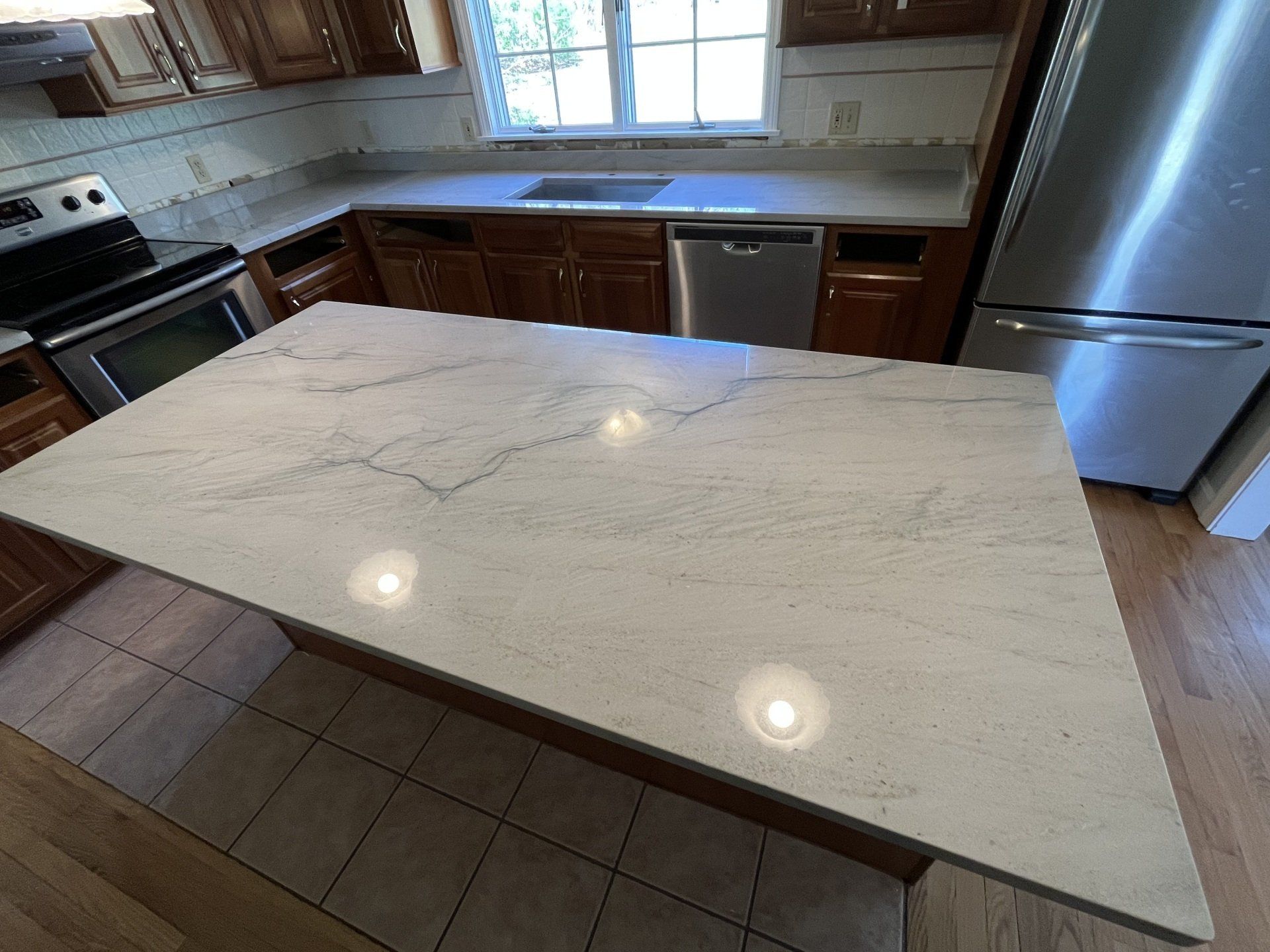 A kitchen with a large white counter top and stainless steel appliances