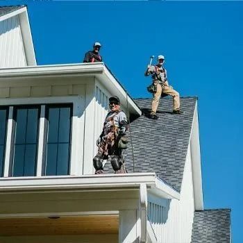 Three roofers on a rooftop, working in bright sunlight.