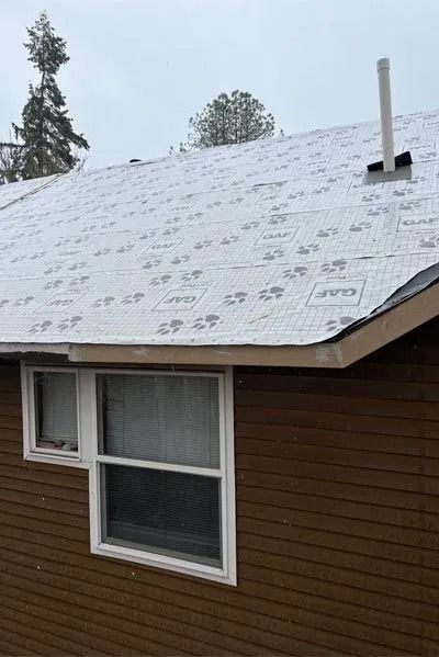 Brown house with a newly installed silver-covered roof, windows, and a chimney.