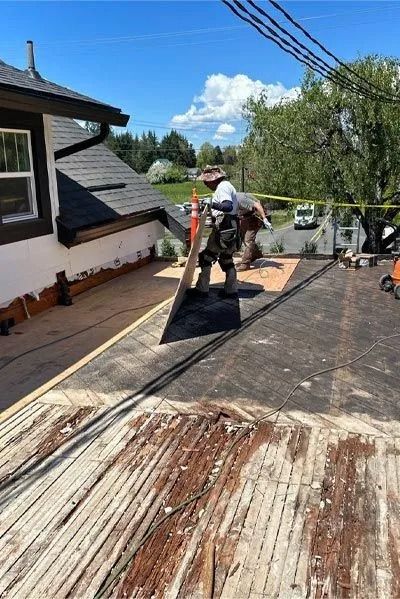 Construction workers on a roof, preparing for repairs.  Wooden structure visible. Sunny day.
