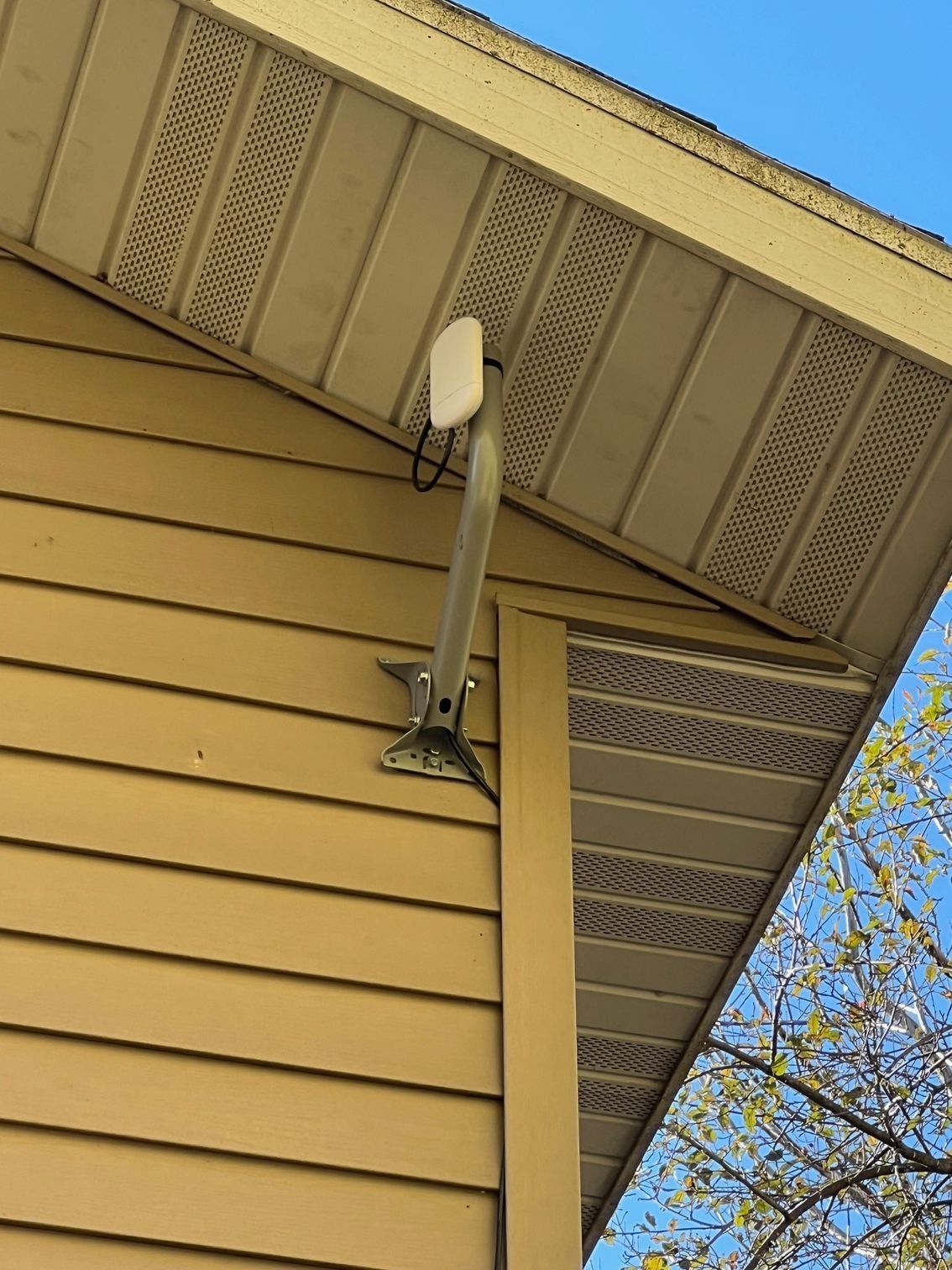 White antenna mounted on a yellow house exterior.