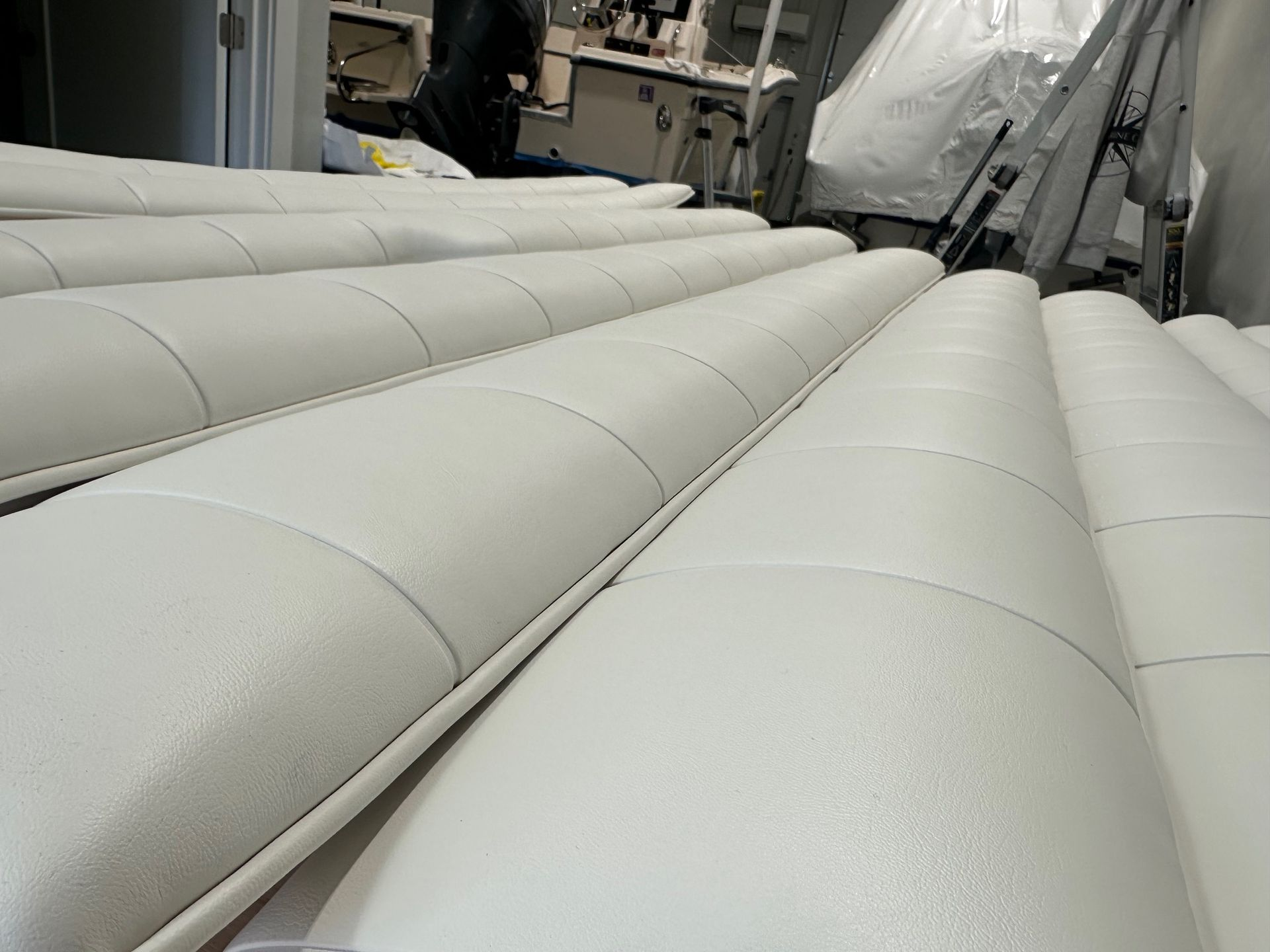 Rows of white, cylindrical upholstered pieces, possibly for seating, in a workshop.
