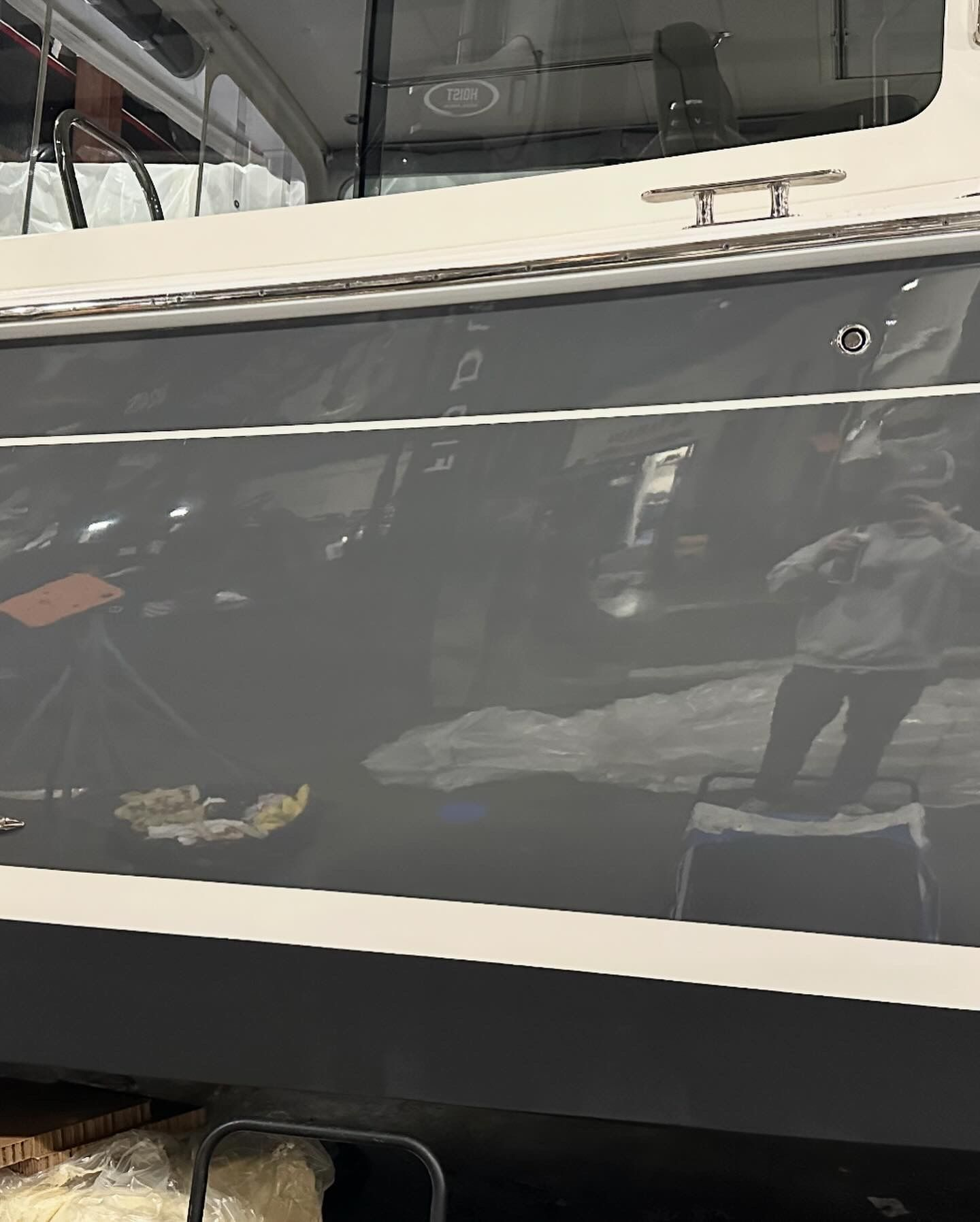 Gray boat side, partially visible, reflecting surroundings, including a person.