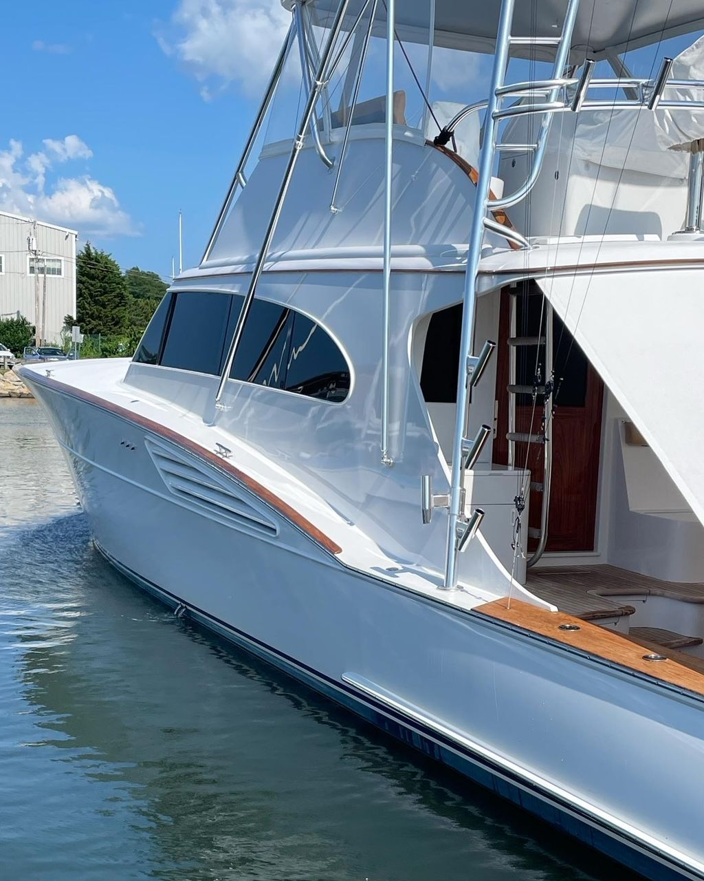 White yacht docked at a pier, blue water, clear sky.