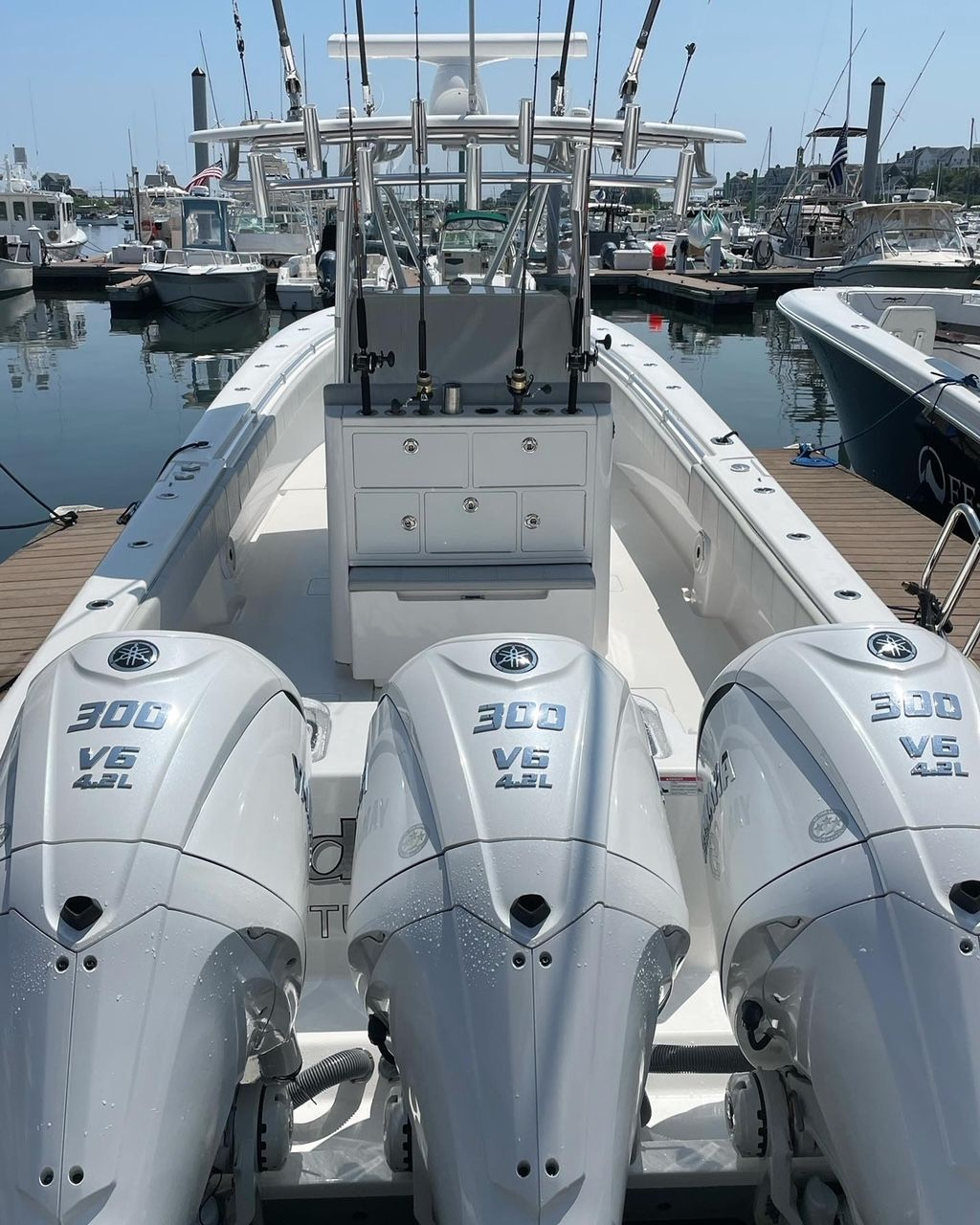 White boat with three outboard motors docked at a marina.