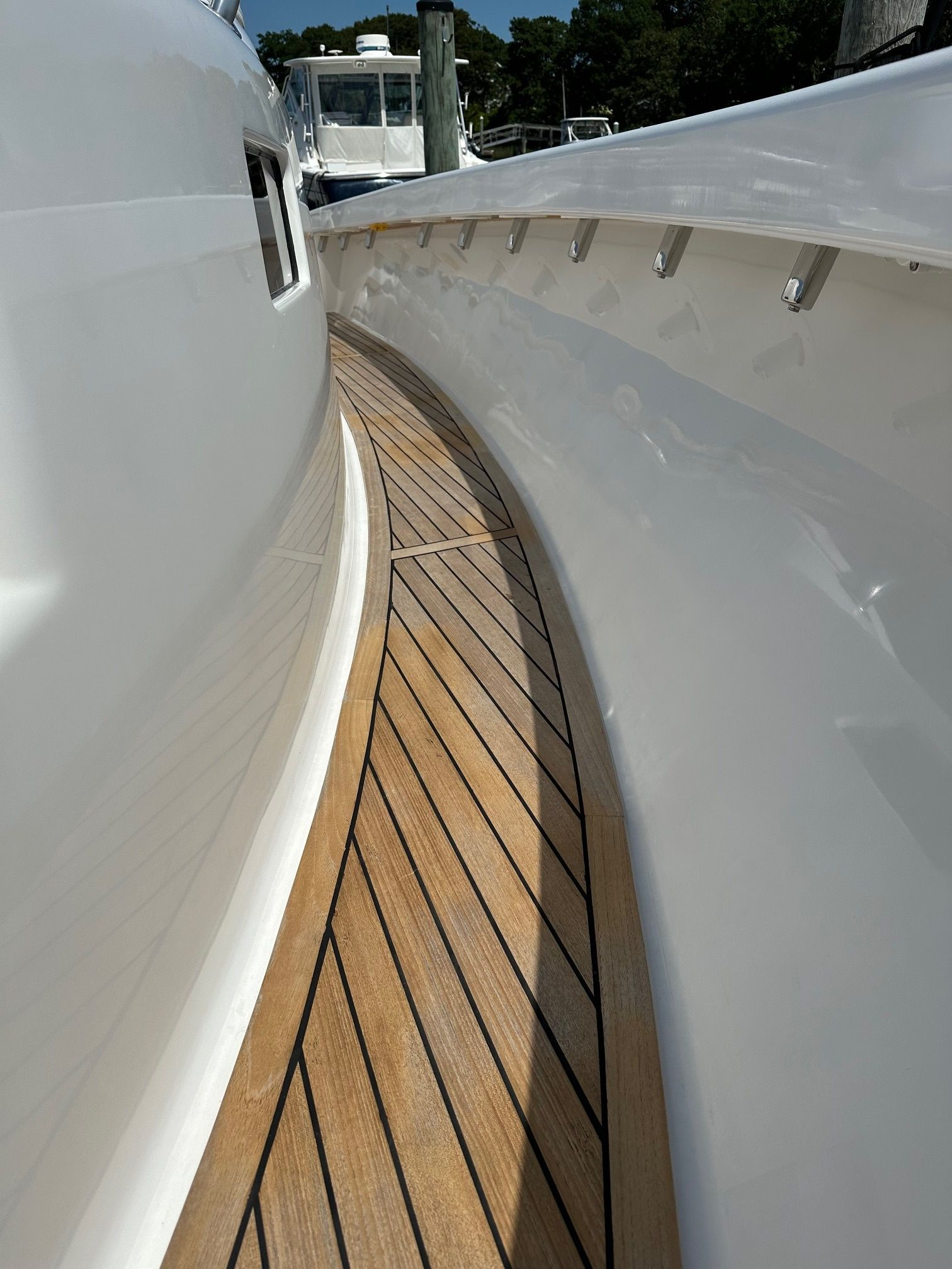 Wooden deck on a white boat with a curved walkway, sunny day.