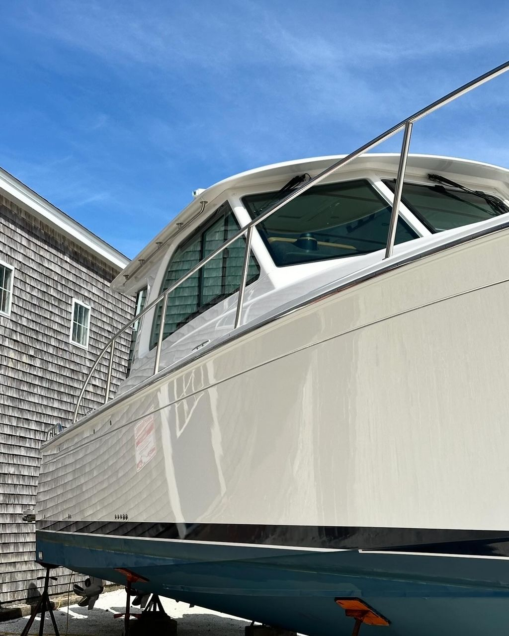 White boat on blue hull, against a gray building under a partly cloudy sky.