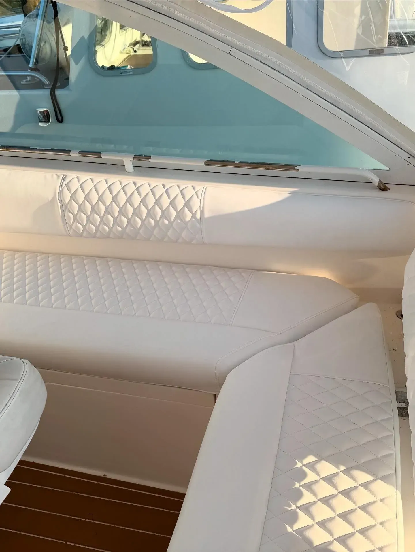 White quilted boat upholstery against a window. The floor is wood.