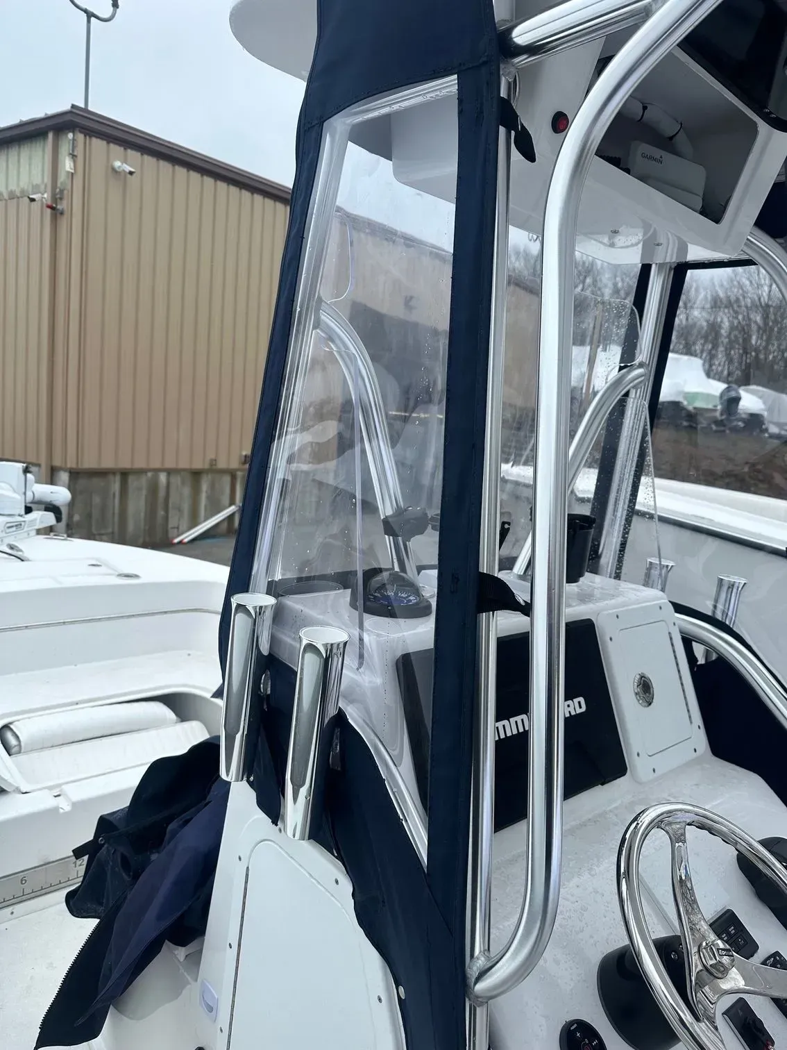 Boat's helm station with a clear enclosure and stainless steel railing. The boat is in a snowy setting.