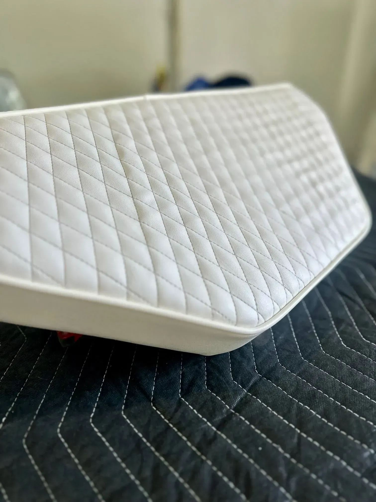 White quilted vinyl cushion on a black padded surface.