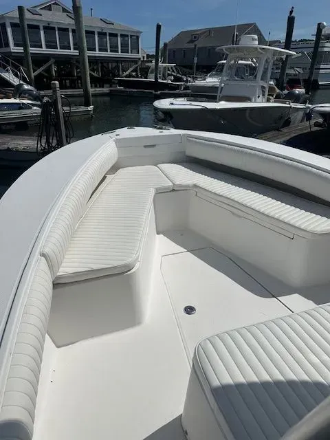 White boat interior with cushioned seating in a harbor on a sunny day.