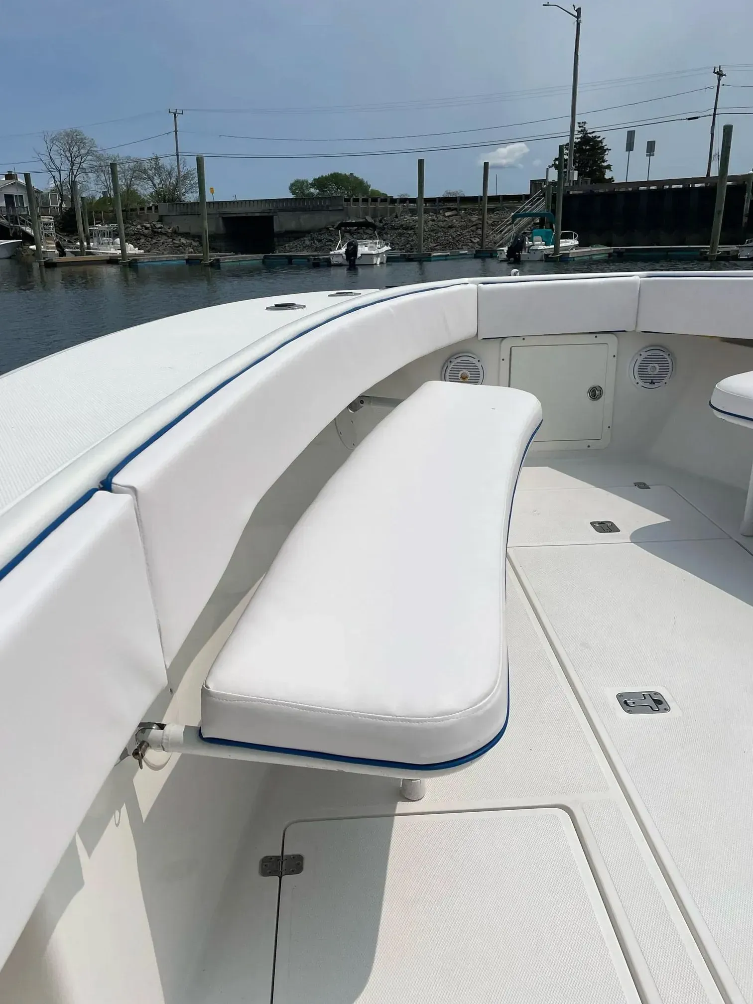 White boat seating with blue trim and cushions. Outdoor setting, water visible.