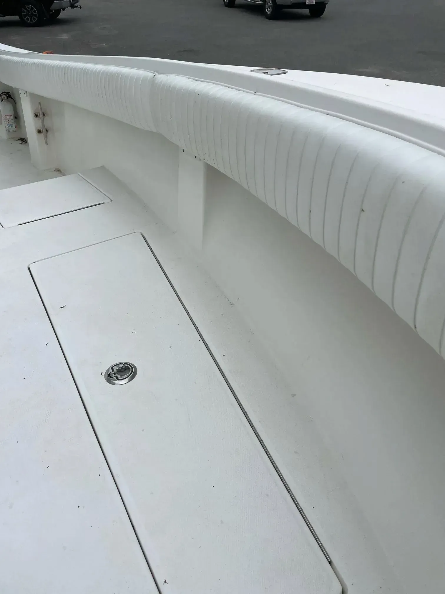 White boat deck with a cushioned railing, storage hatch visible.