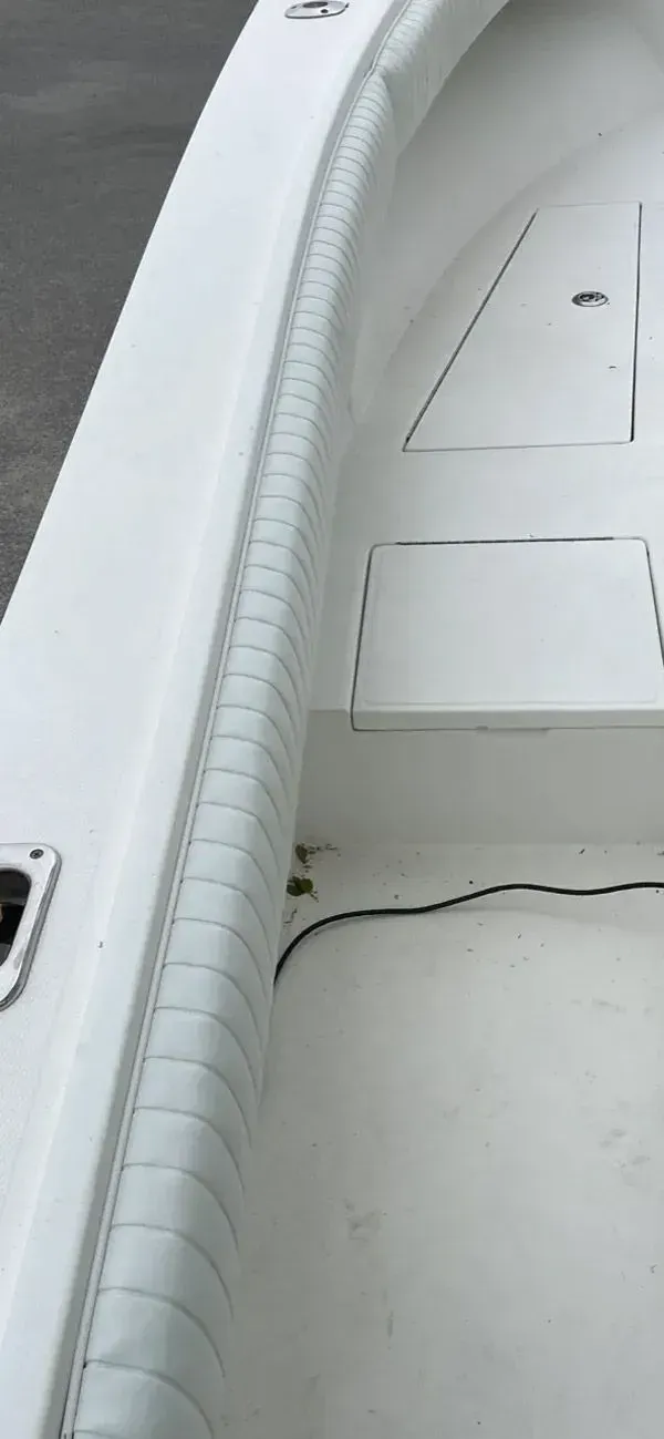 White interior of a boat with cushioned side rails and storage compartments.