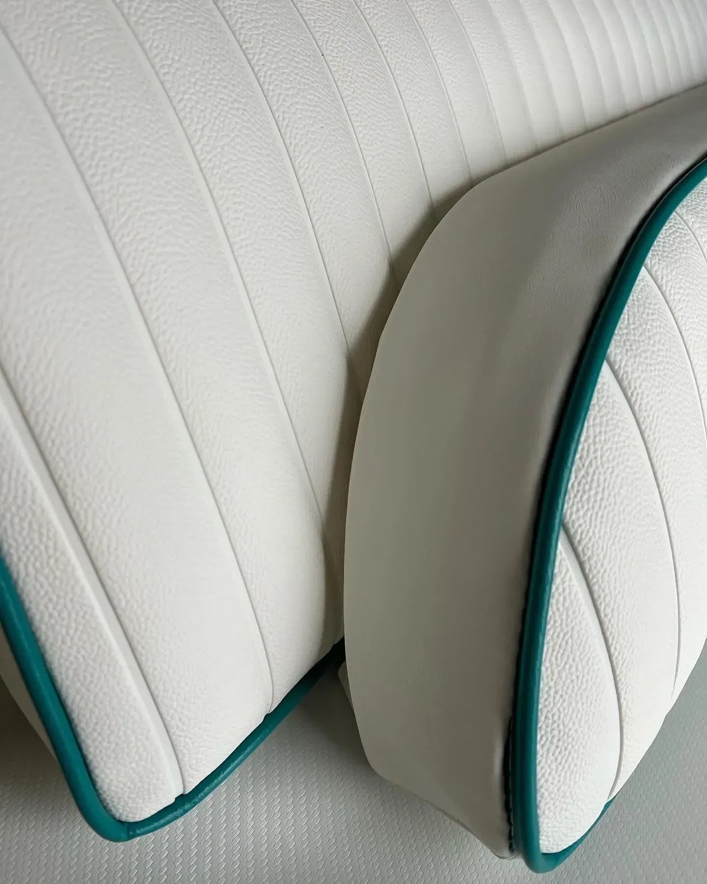 White boat cushions with teal piping, vertically ribbed design.
