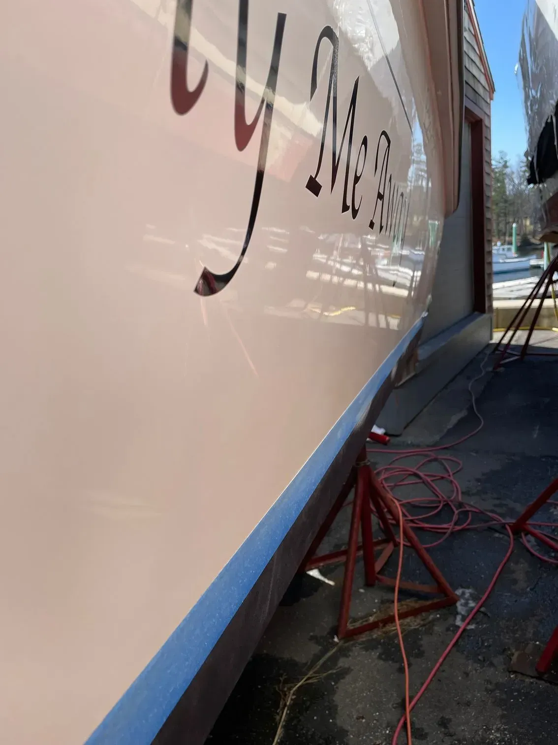 A close-up view of the white hull of a boat in storage, showing the text 