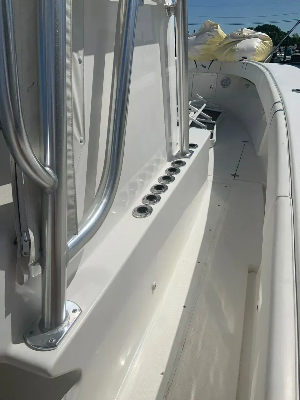 A row of circular rod holders mounted along the side of a white boat center console, with metal railings visible.