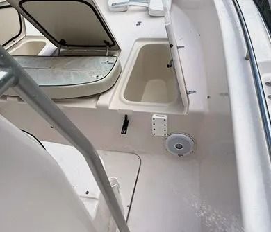 The interior deck of a boat featuring open storage hatches, a built-in speaker, and a metal railing.