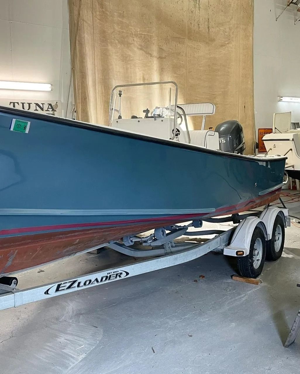 A blue center-console boat sits on an EZ Loader trailer inside a storage facility.