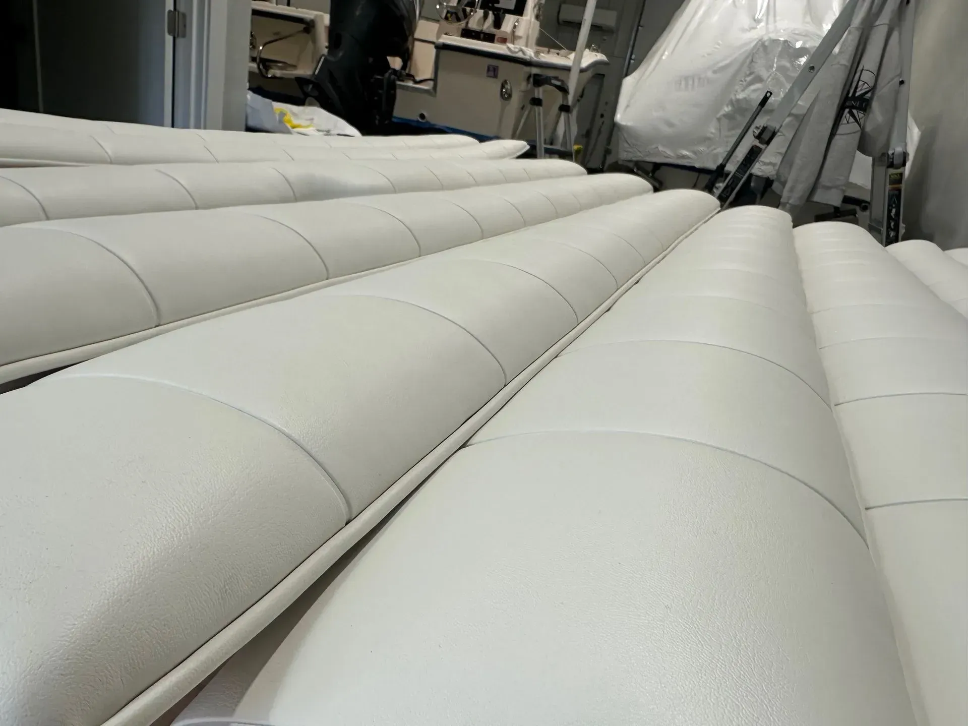 Rows of padded white vinyl marine upholstery sections laid out in a workshop.