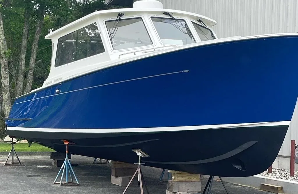 Person using a sander on a red wall. Close-up shows tool and hands.
