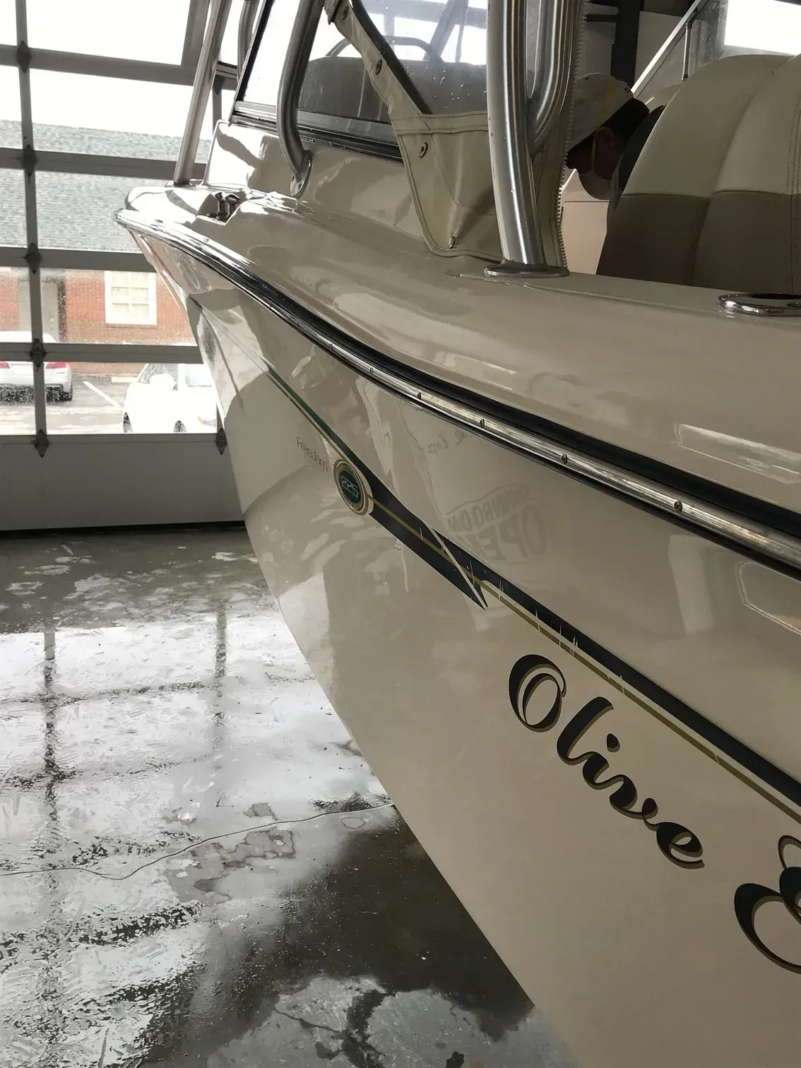 A side view of a cream-colored boat inside a garage, showing the name 