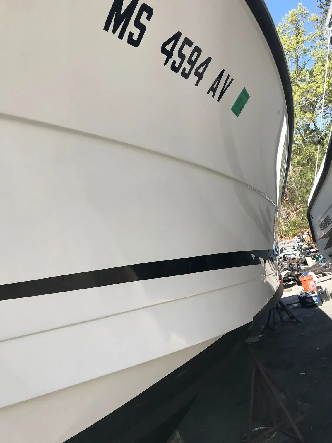 Close-up of a white boat hull in a yard featuring black pinstripes and the registration number MS 4594 AV.