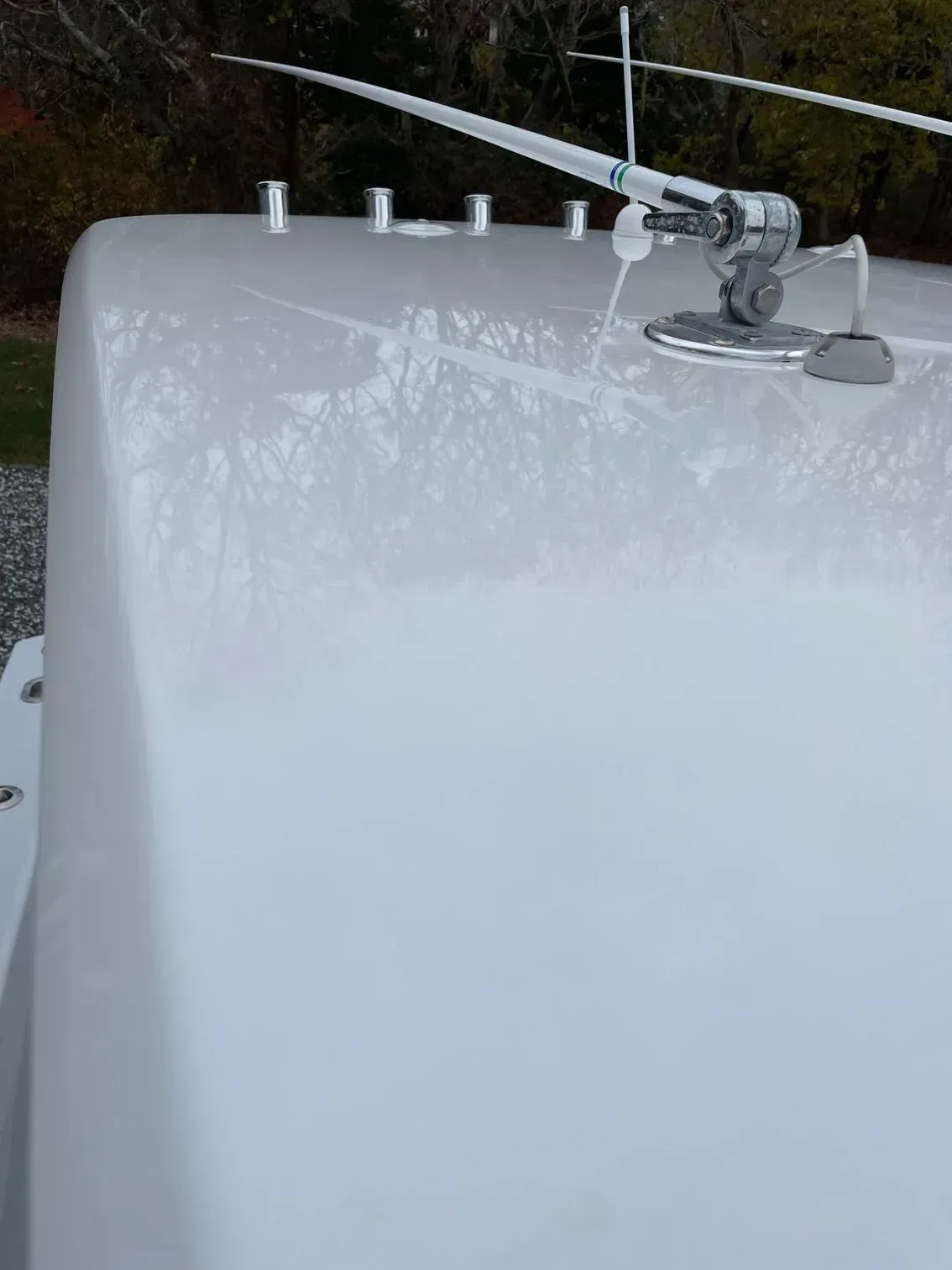 A white boat roof with a mounted antenna and several cylindrical fishing rod holders in the background.