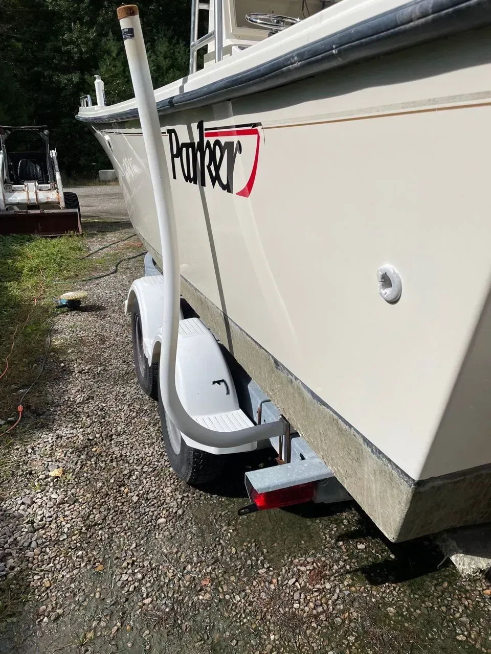A close-up of the side of a cream-colored Parker boat on a trailer, showing a curved white PVC guide pole on the fender.