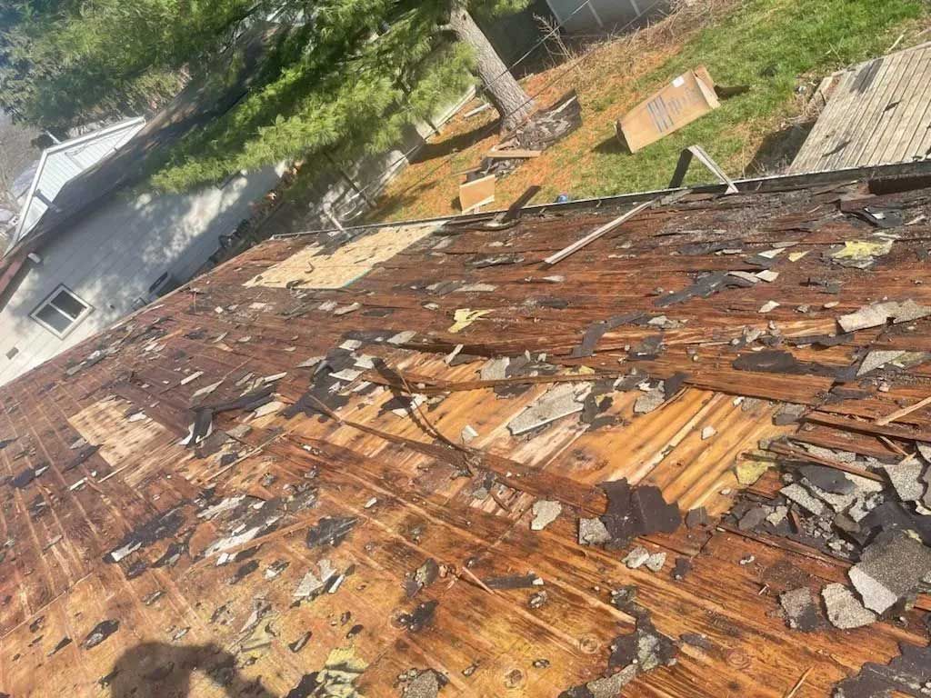 A damaged, weathered roof with peeling material, viewed from above.