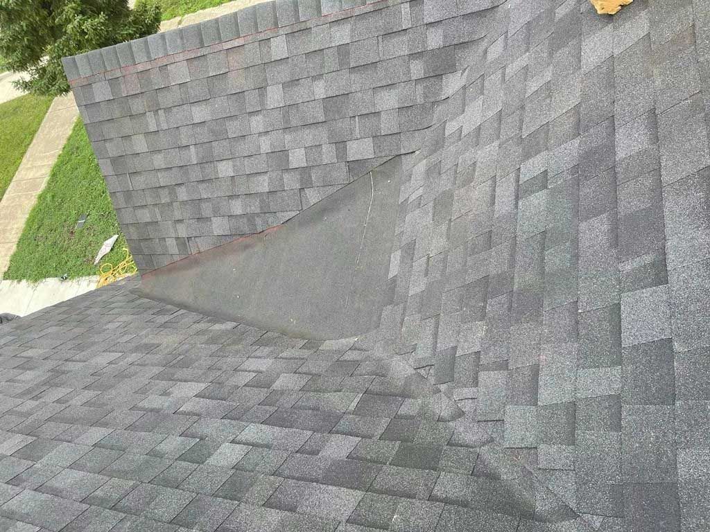 Gray asphalt shingle roof with a valley. The shingles are slightly faded and weathered.