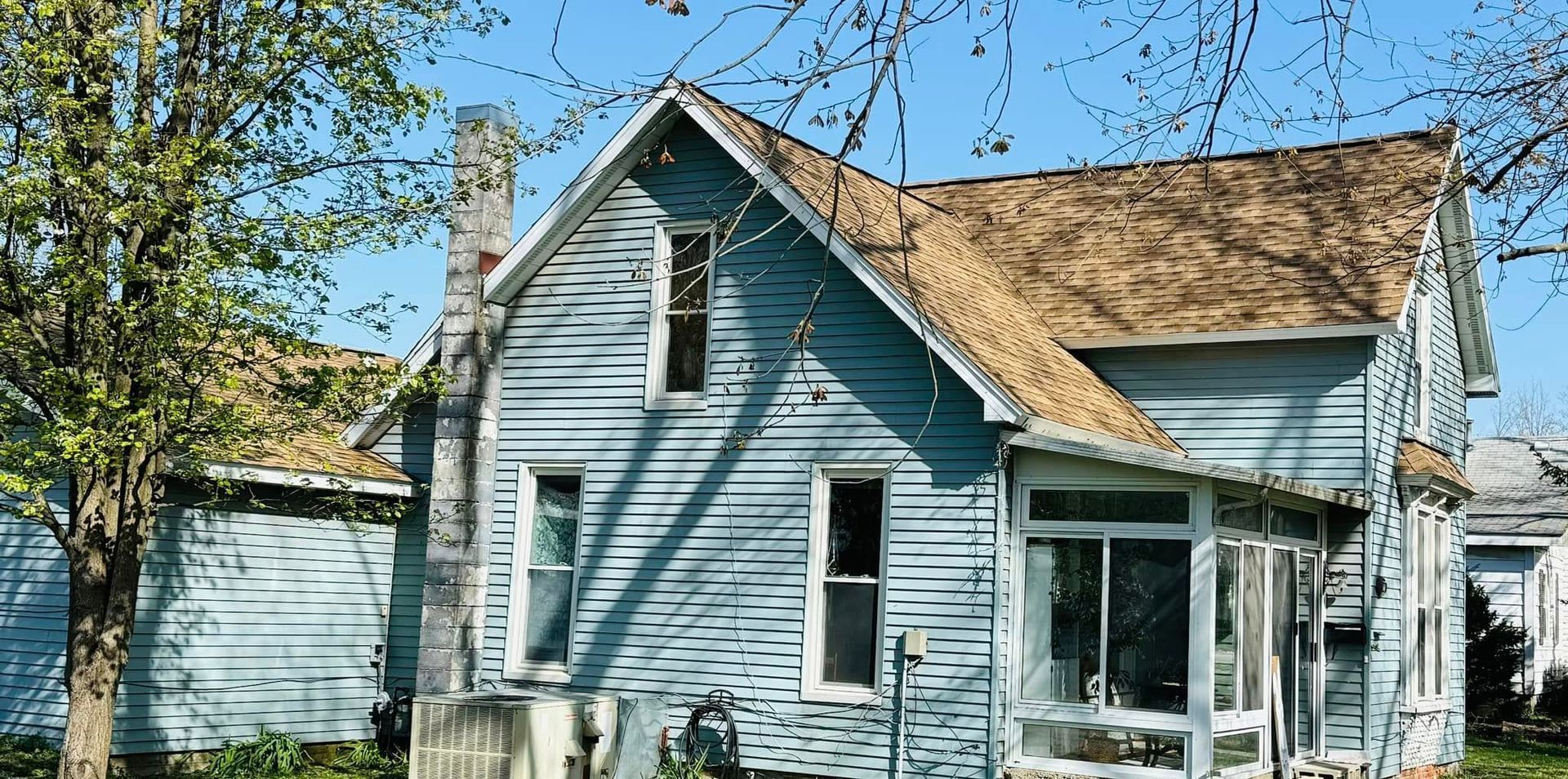 Blue house with a brown roof under a blue sky.