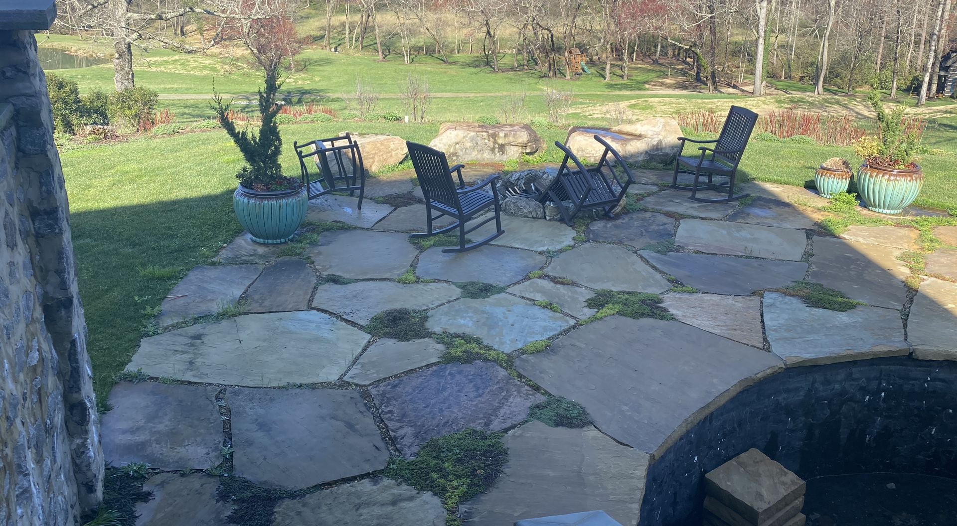 A stone patio with rocking chairs and a fire pit.