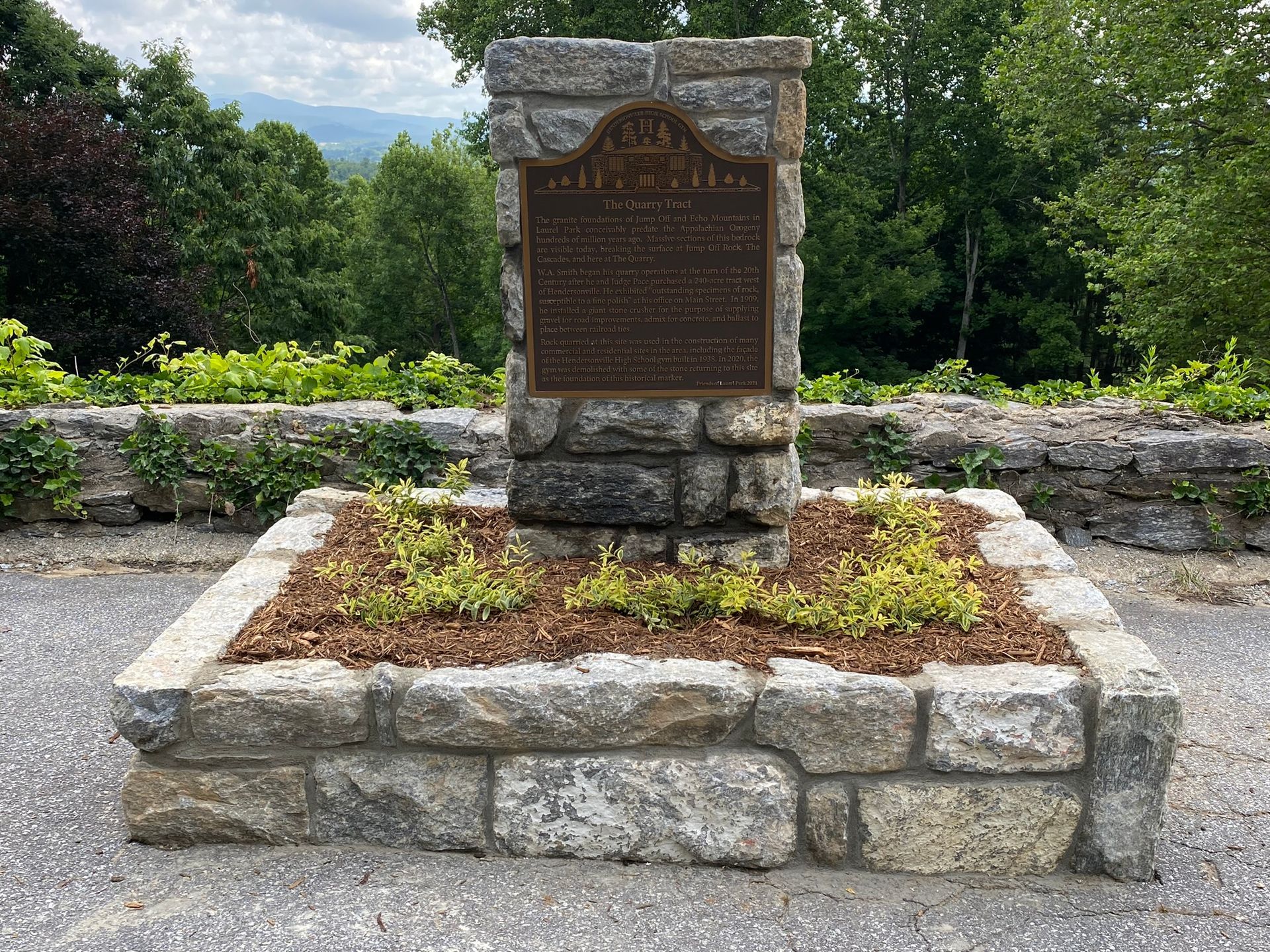 A stone monument with a plaque on top of it in a garden.