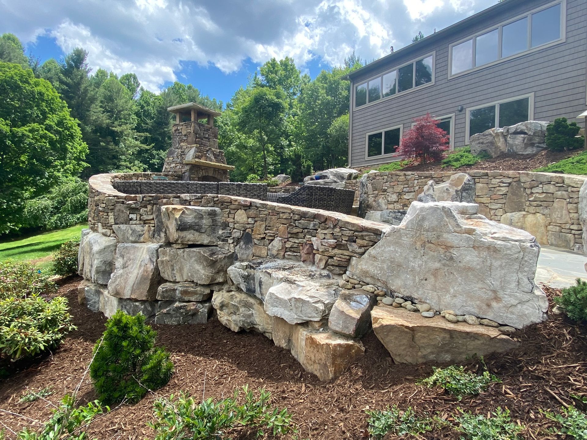 A large stone wall with a fountain in the backyard of a house.