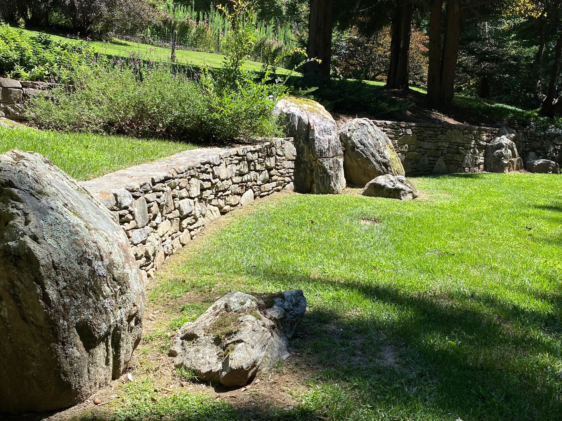 A stone wall is surrounded by rocks in a park.
