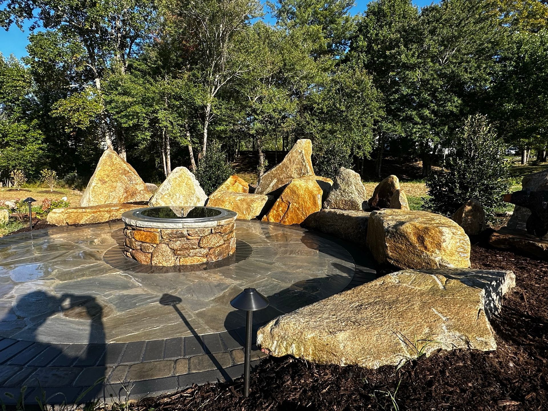 There is a fire pit in the middle of the patio surrounded by rocks.