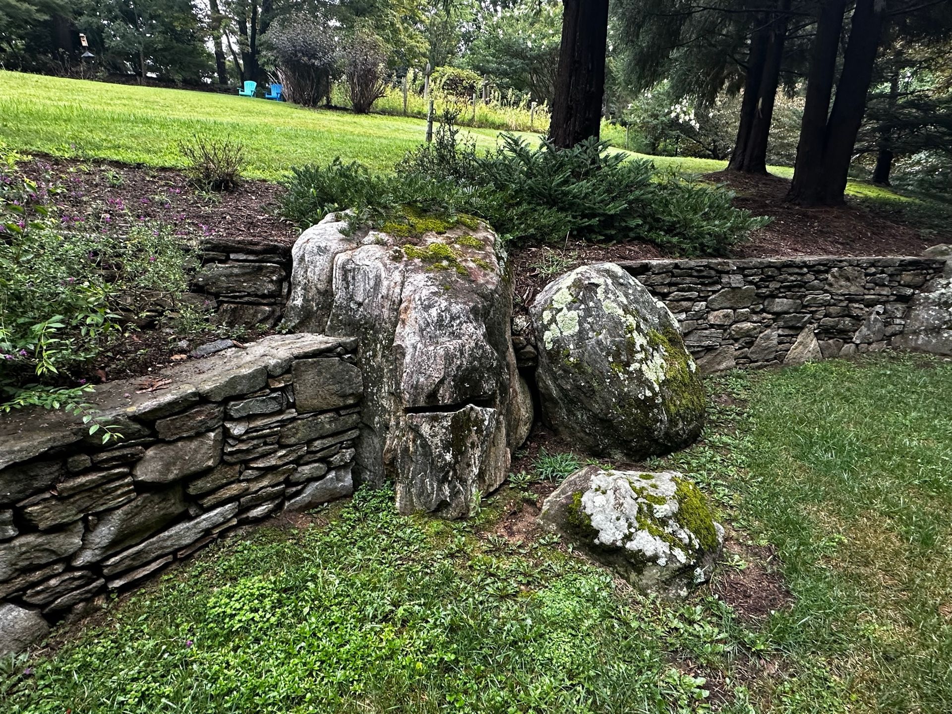 A stone wall is surrounded by rocks and grass in a park.