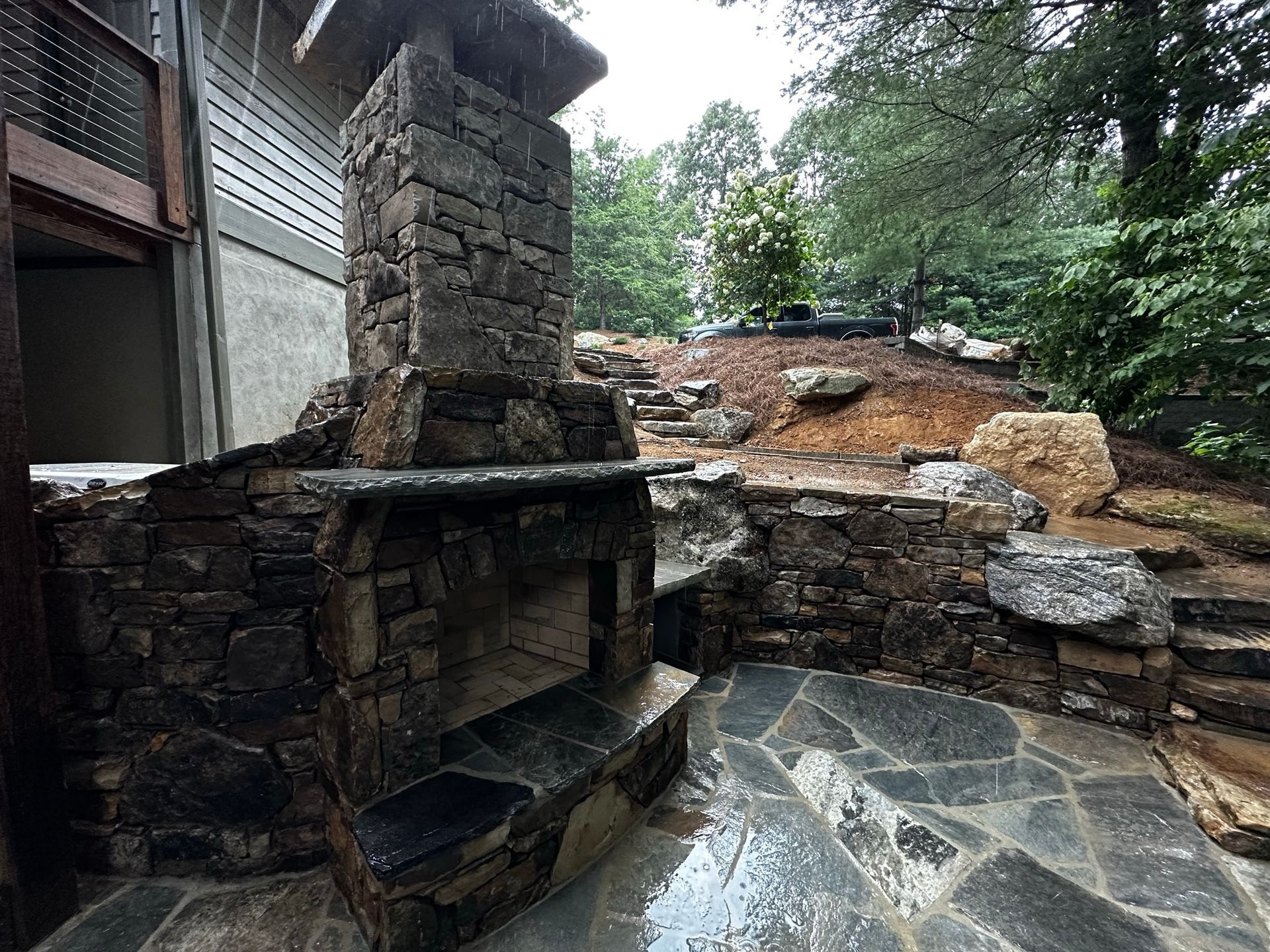 There is a stone fireplace in the backyard of a house.