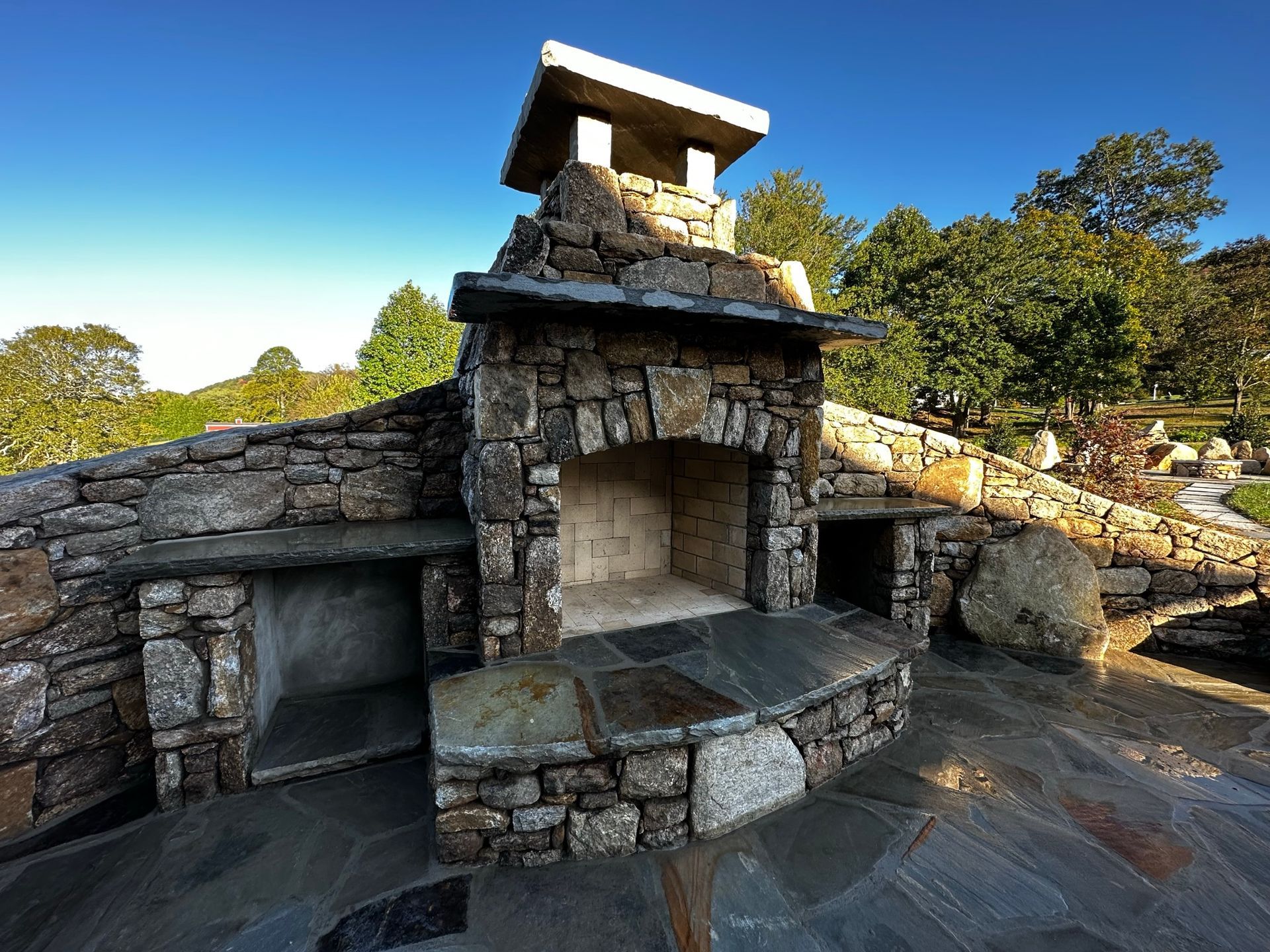A stone fireplace with a chimney on top of it.
