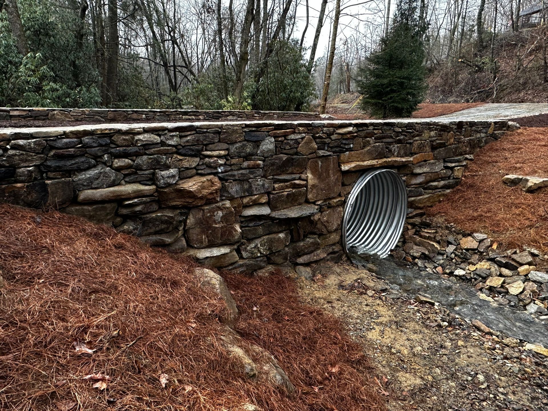 A stone wall with a metal pipe coming out of it.
