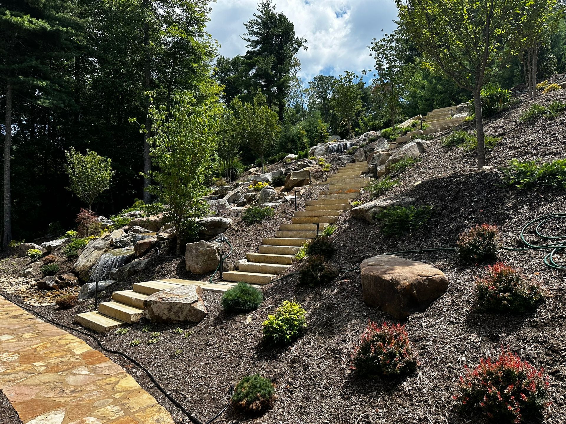 There are stairs leading up to the top of a hill surrounded by rocks and trees.