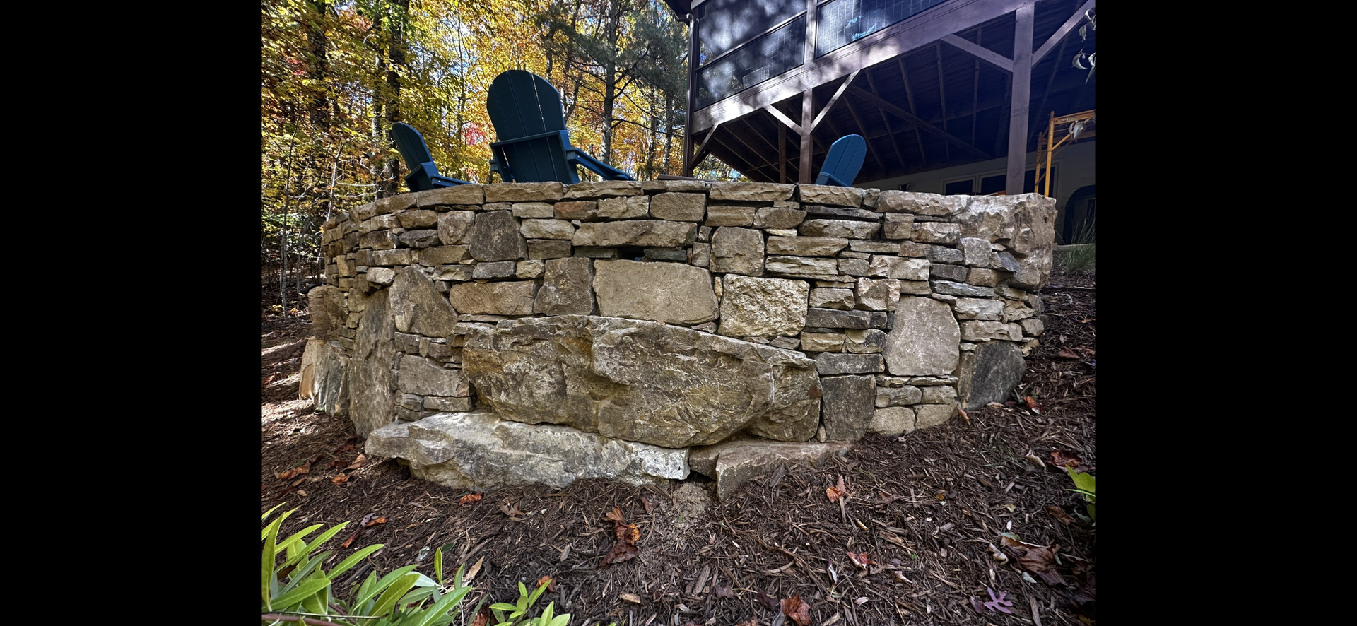 There is a stone wall in the middle of the woods.