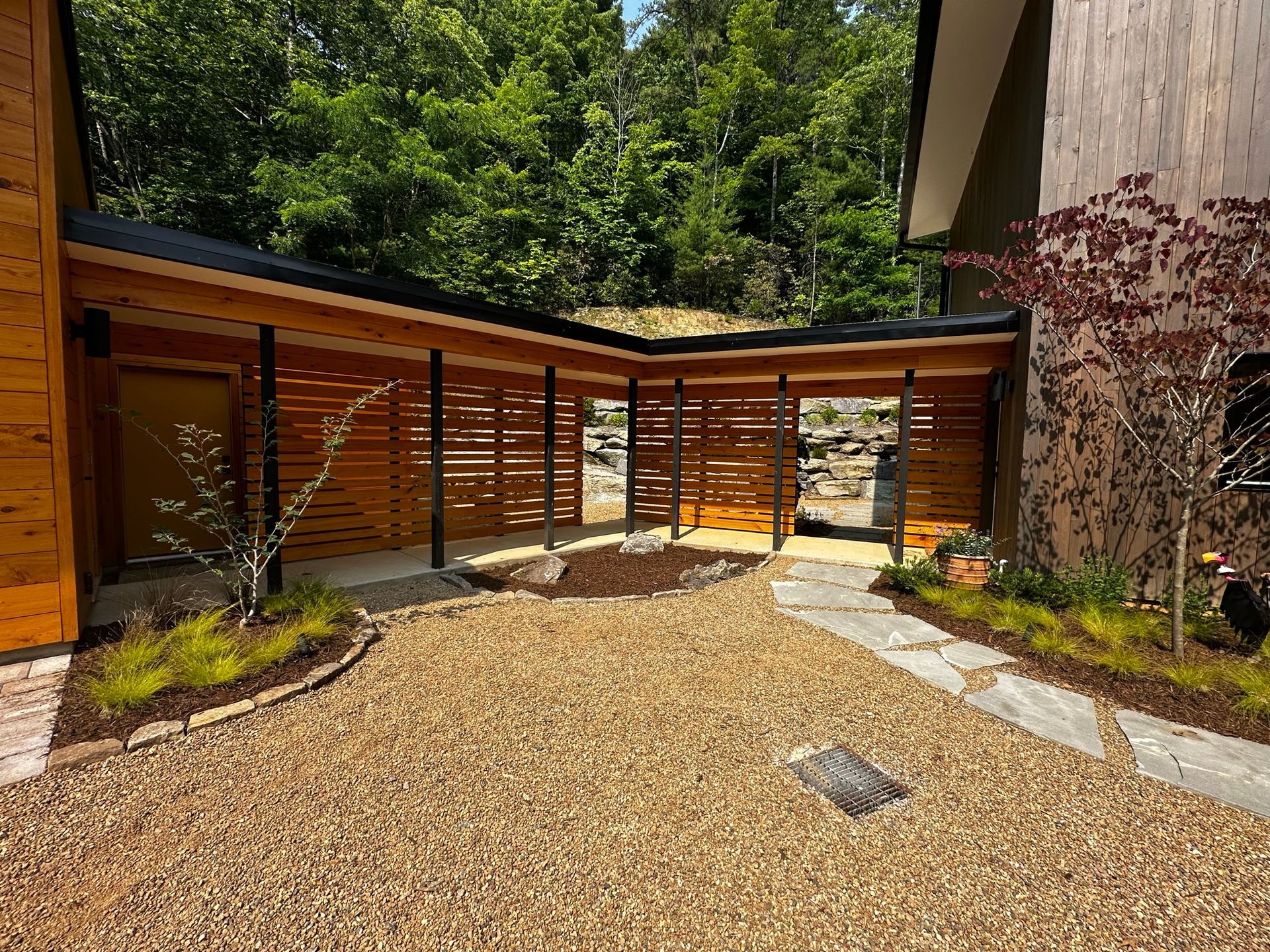 A wooden house with a gravel driveway in front of it.