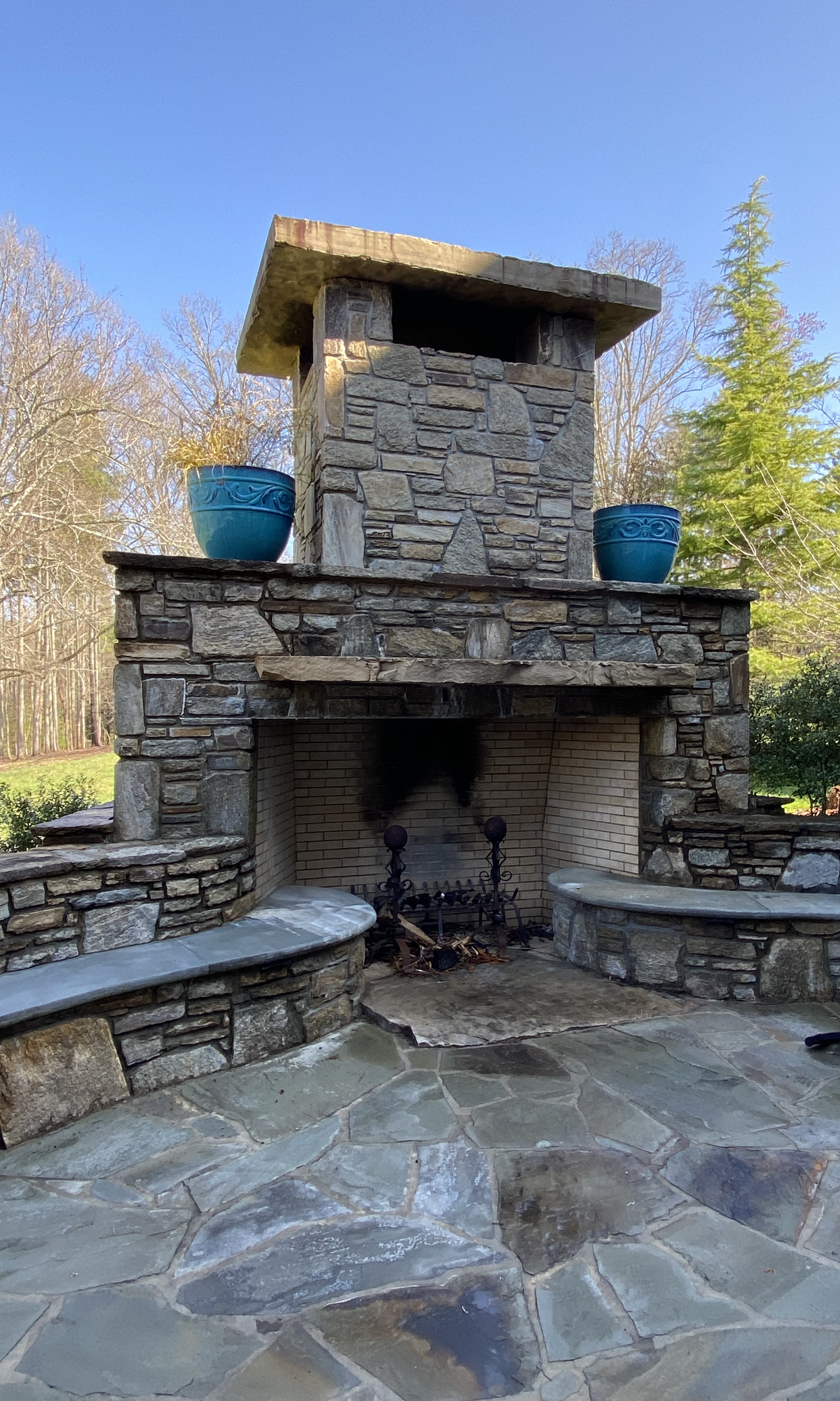 A large stone fireplace is sitting on top of a stone patio.
