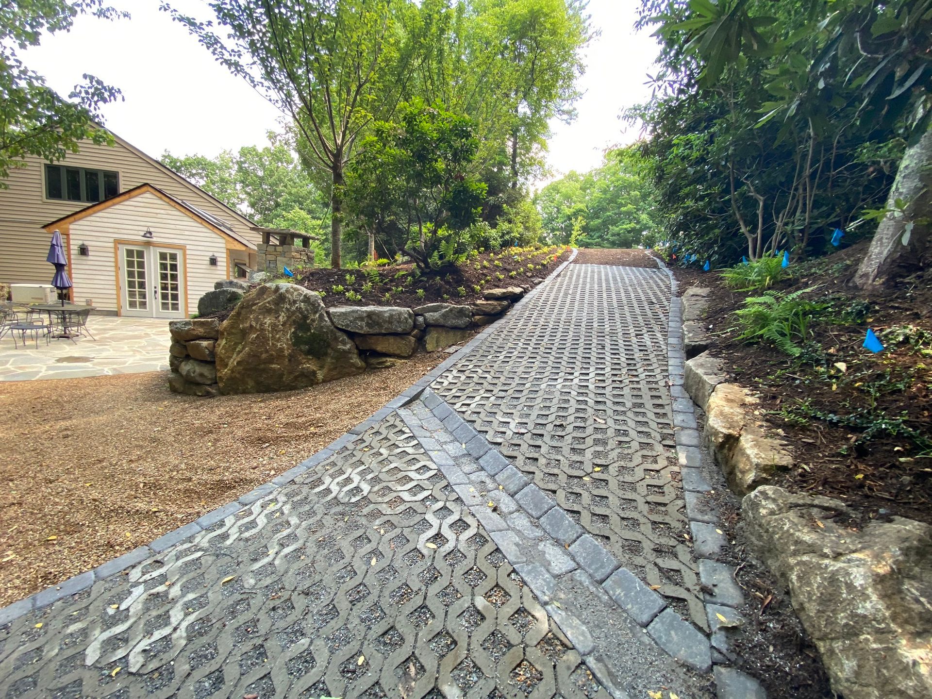 A brick walkway leading to a house in the woods.