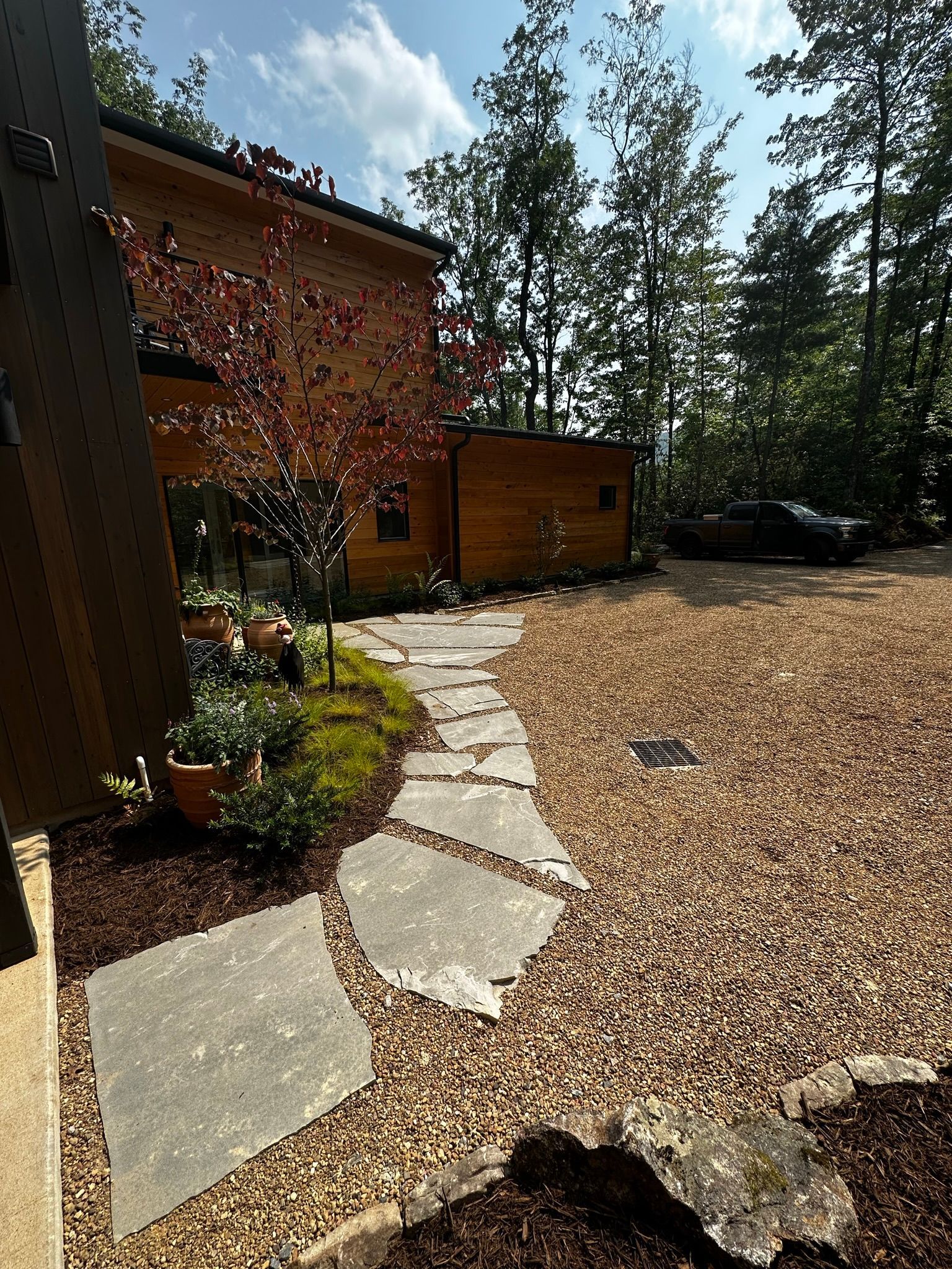 A stone walkway leading to a house in the woods.